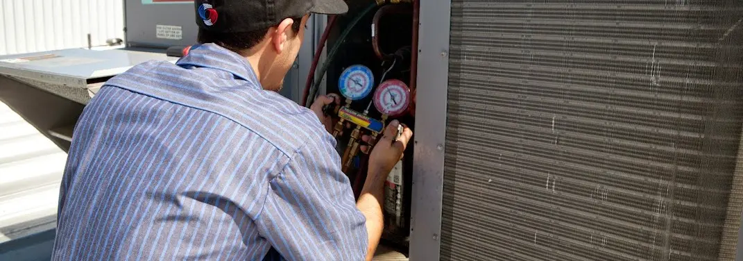 HVAC technician servicing a condenser unit in Oradell